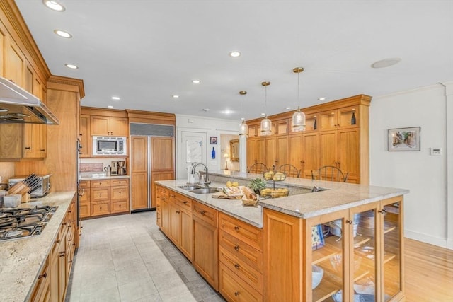 kitchen featuring built in appliances, recessed lighting, a spacious island, a sink, and light stone countertops