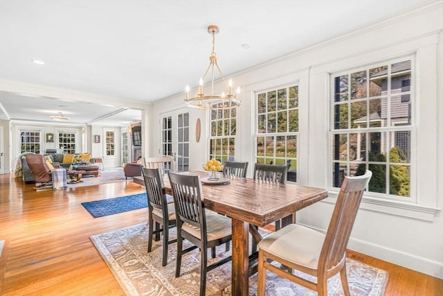 dining space featuring light wood-style floors, crown molding, baseboards, and an inviting chandelier