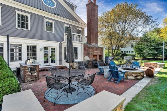 view of patio featuring an outdoor fire pit, french doors, and a balcony