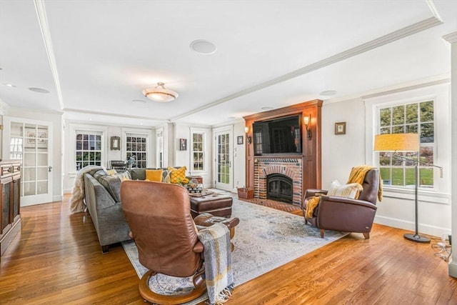 living area with crown molding, baseboards, a fireplace, and hardwood / wood-style floors