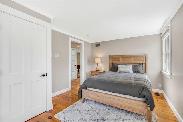 bedroom with visible vents, crown molding, light wood-style flooring, and baseboards