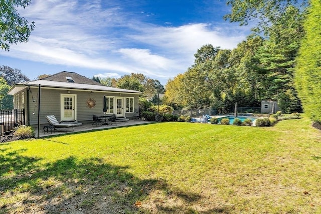 rear view of house with a patio, a lawn, fence, and a fenced in pool