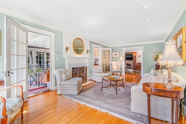 living room featuring a high end fireplace, ornamental molding, wood finished floors, french doors, and recessed lighting