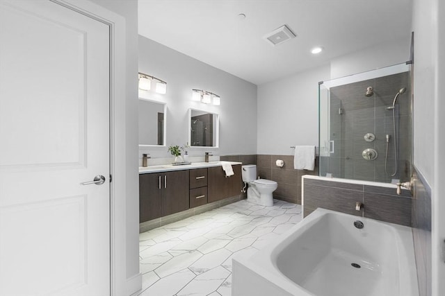 full bathroom with a tile shower, double vanity, toilet, a bath, and tile walls