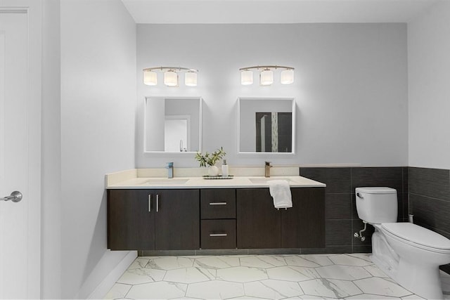 bathroom featuring a sink, toilet, double vanity, and marble finish floor