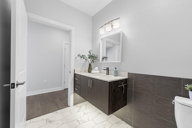 bathroom with toilet, vanity, and marble finish floor