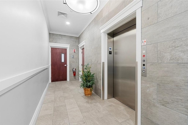 corridor with elevator, tile walls, ornamental molding, visible vents, and light tile patterned flooring