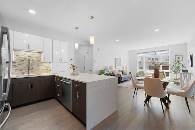 kitchen featuring light wood finished floors, a sink, appliances with stainless steel finishes, and white cabinetry