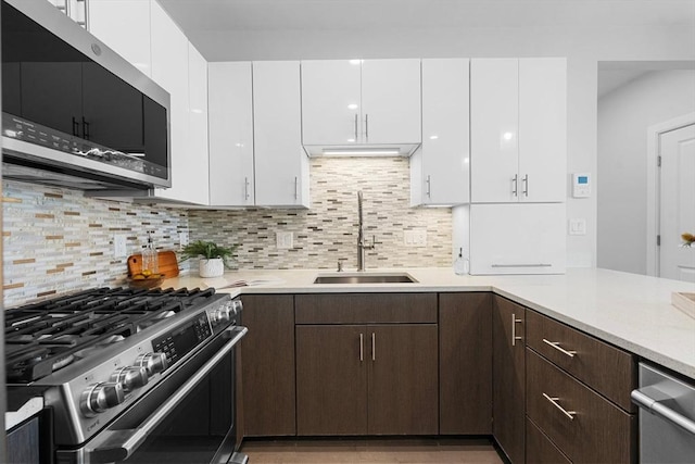 kitchen with white cabinetry, stainless steel appliances, light countertops, and a sink