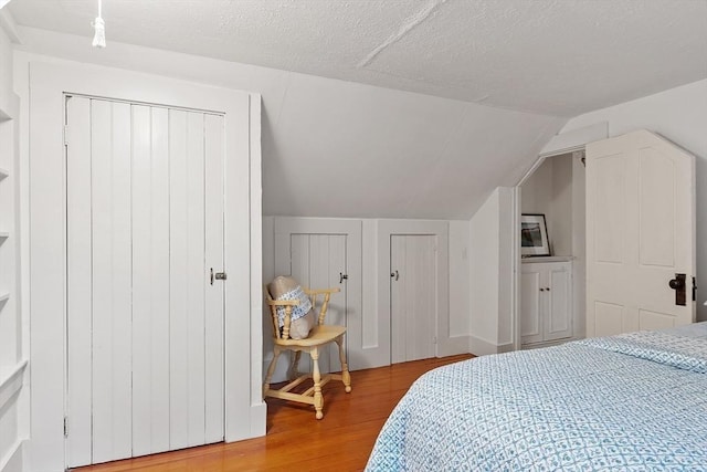14 Upland Rd, Andover, MA 01810 - bedroom with wood finished floors, vaulted ceiling, two closets, and a textured ceiling