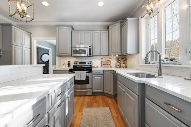 kitchen with appliances with stainless steel finishes, sink, hanging light fixtures, and gray cabinetry