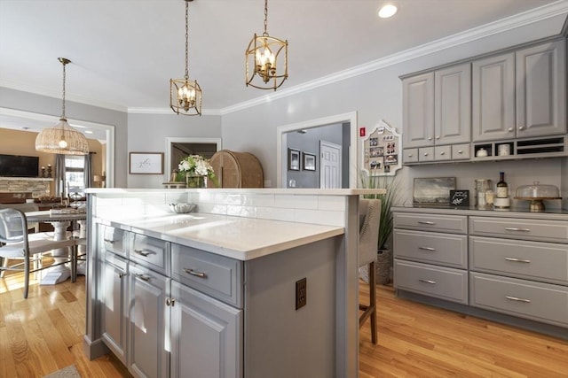 kitchen featuring gray cabinets, hanging light fixtures, and light hardwood / wood-style flooring