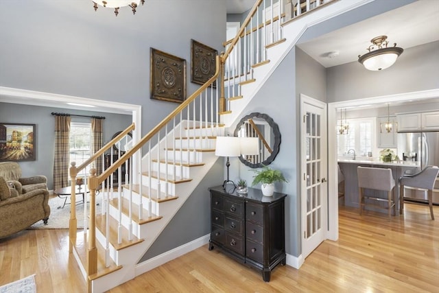 staircase featuring an inviting chandelier, hardwood / wood-style flooring, and a high ceiling