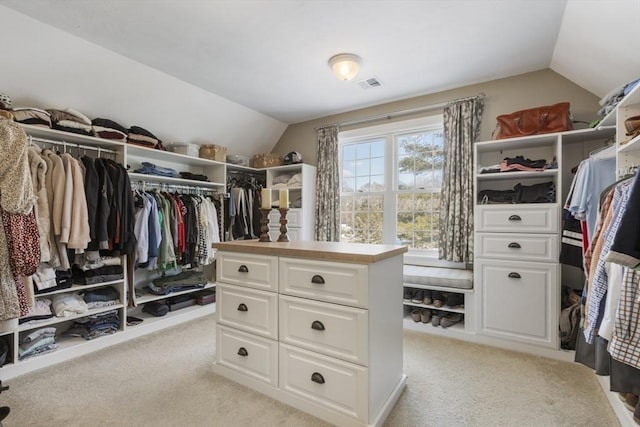 spacious closet with vaulted ceiling and light colored carpet