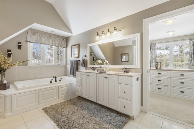 bathroom featuring vanity, vaulted ceiling, tile patterned floors, and a bathing tub