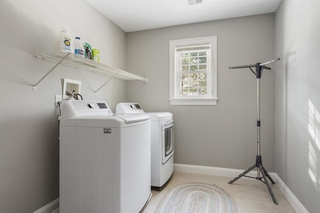 laundry area with washer and dryer and light tile patterned floors