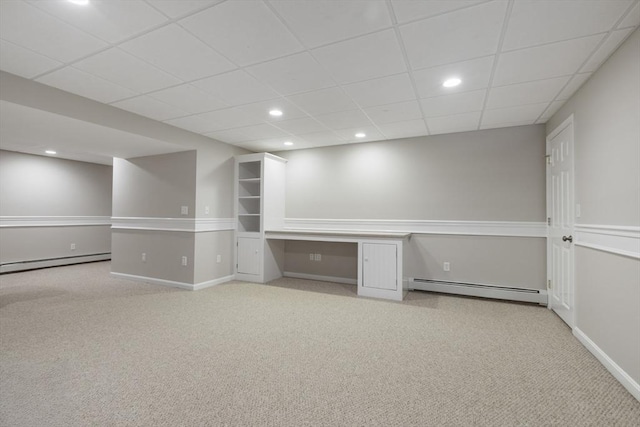 basement with a paneled ceiling, a baseboard heating unit, and light carpet