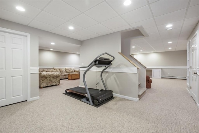 exercise room with light colored carpet, a drop ceiling, and a baseboard heating unit