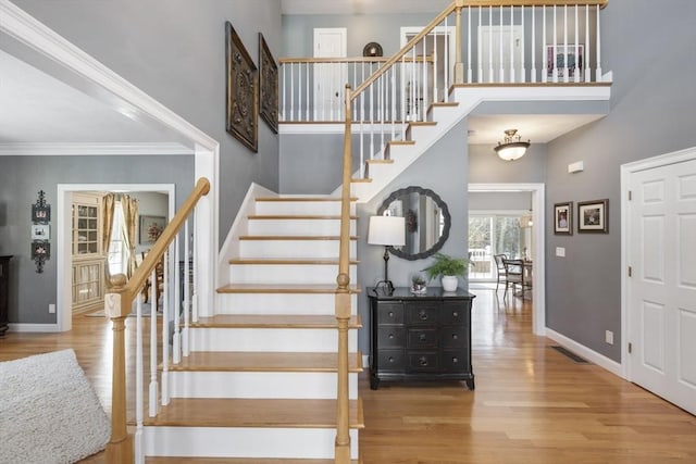 stairway with hardwood / wood-style flooring, crown molding, and a high ceiling