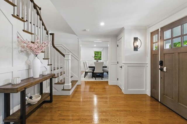290 Lyman Rd, Milton, MA 02186 - foyer featuring stairs, a decorative wall, light wood-style floors, ornamental molding, and a wainscoted wall