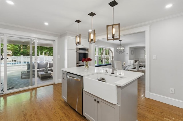 290 Lyman Rd, Milton, MA 02186 - kitchen with appliances with stainless steel finishes, a sink, a center island with sink, light countertops, and light wood finished floors