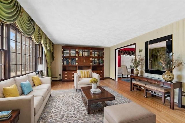 living room with a baseboard heating unit and wood finished floors