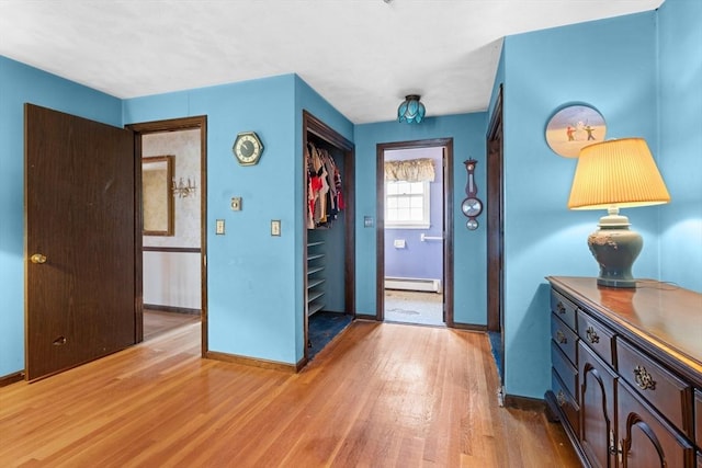 entryway featuring a baseboard radiator, baseboards, and light wood finished floors