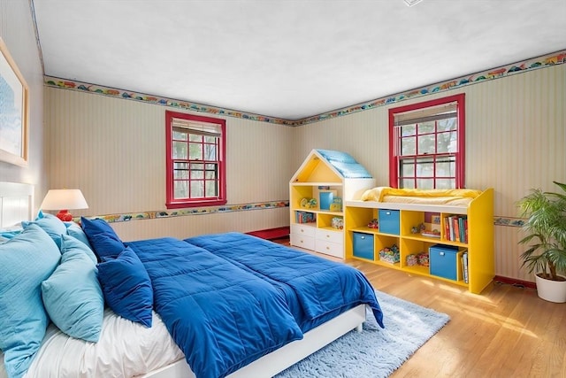 bedroom with wood finished floors and wallpapered walls