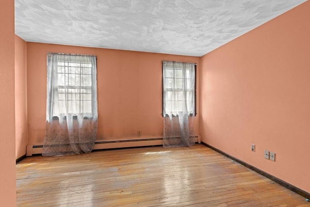spare room featuring wood-type flooring, a textured ceiling, and baseboards