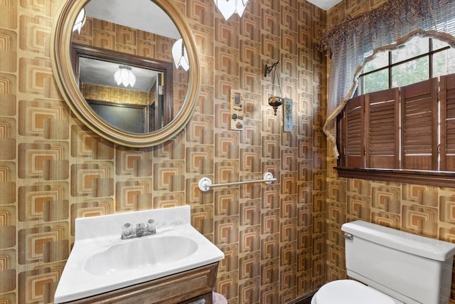 half bath featuring toilet, a sink, and wallpapered walls