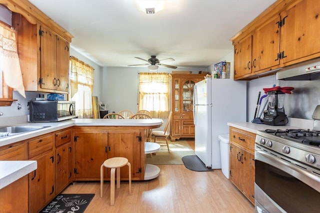 101 Primrose St, Fall River, MA 02720 - kitchen featuring black microwave, gas range, light countertops, under cabinet range hood, and light wood-style flooring
