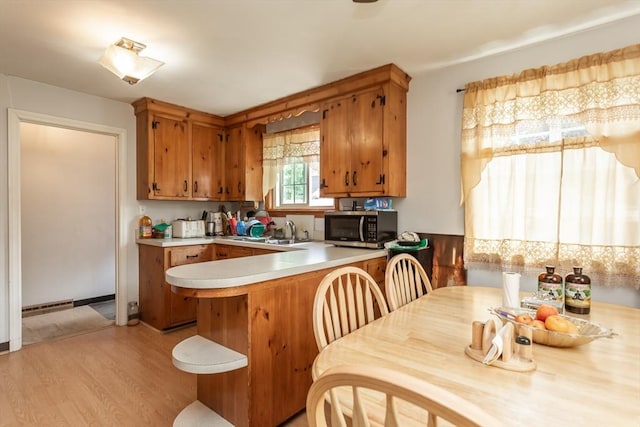 101 Primrose St, Fall River, MA 02720 - kitchen featuring stainless steel microwave, brown cabinetry, light wood-style flooring, and light countertops
