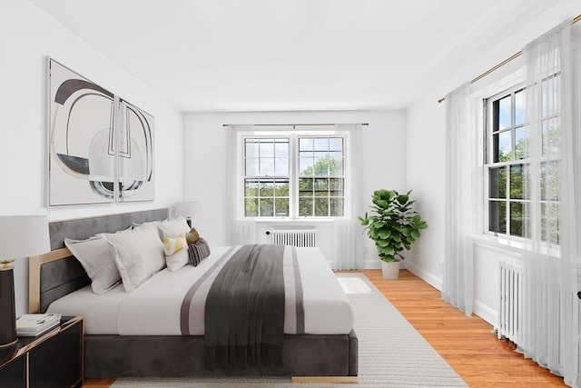 bedroom featuring radiator, light wood-type flooring, and baseboards