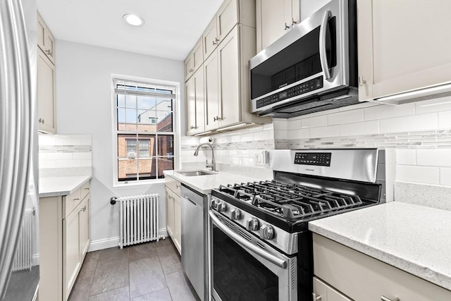 kitchen with radiator heating unit, stainless steel appliances, a sink, backsplash, and recessed lighting