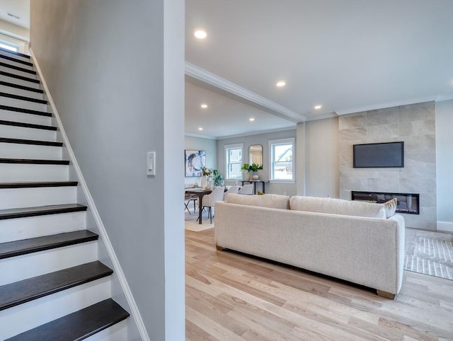 living room featuring crown molding, a fireplace, and light hardwood / wood-style flooring