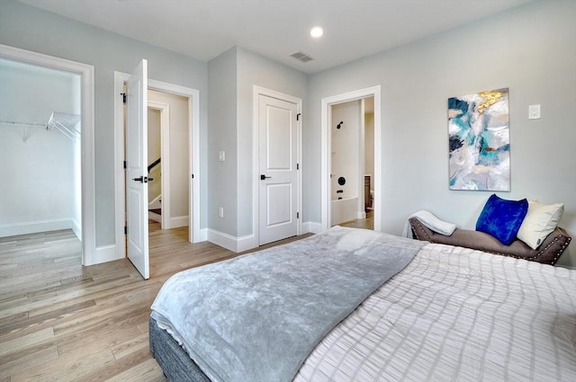 bedroom featuring a spacious closet, light hardwood / wood-style flooring, and a closet