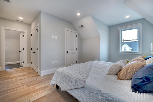 bedroom featuring lofted ceiling and light wood-type flooring