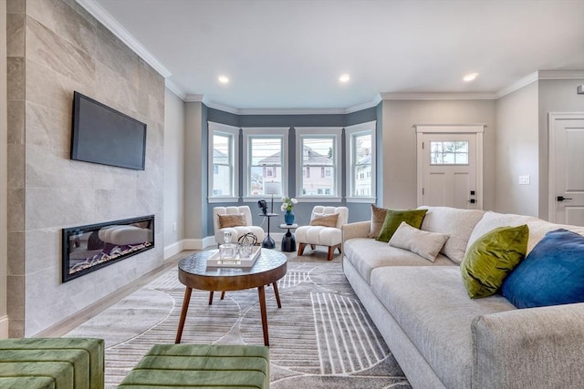 living room featuring a tile fireplace, ornamental molding, and hardwood / wood-style flooring