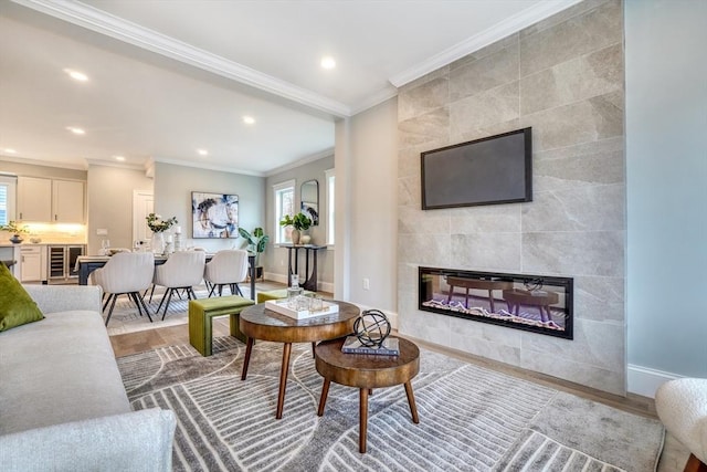 living room with hardwood / wood-style floors, ornamental molding, and a tiled fireplace