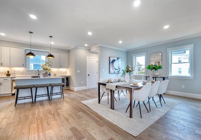 dining space with wine cooler, crown molding, and light wood-type flooring