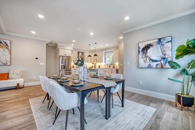 dining area with crown molding, light hardwood / wood-style flooring, and sink