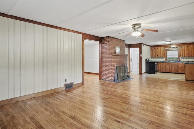 3 Cranberry Meadow Shore Rd, Charlton, MA 01507 - unfurnished living room with light wood-style flooring, ceiling fan, a brick fireplace, and wooden walls