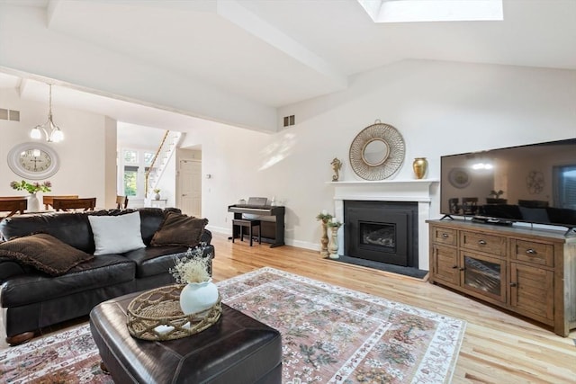 74 Hidden Bay Dr Unit 74, Dartmouth, MA 02748 - living area with light wood-type flooring, vaulted ceiling, a fireplace, a skylight, and a chandelier