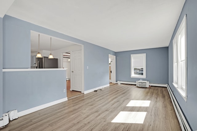 unfurnished living room featuring a baseboard heating unit and hardwood / wood-style floors