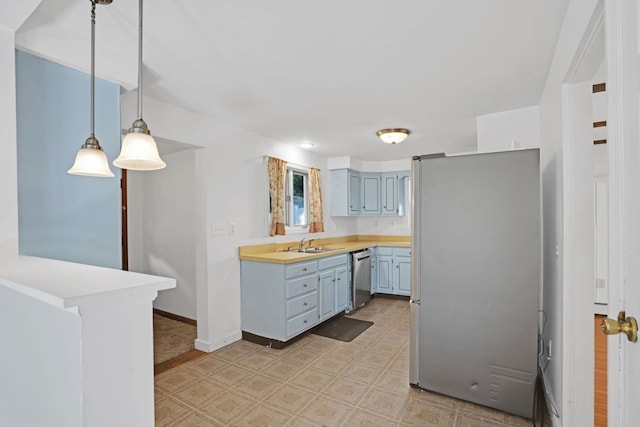 kitchen featuring appliances with stainless steel finishes, kitchen peninsula, sink, and decorative light fixtures