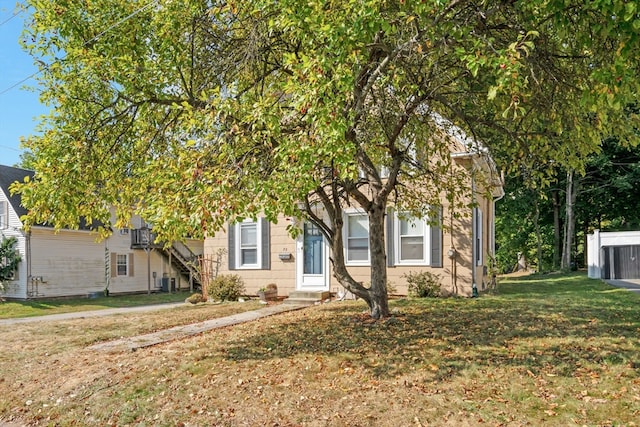 view of property hidden behind natural elements featuring a front yard and cooling unit