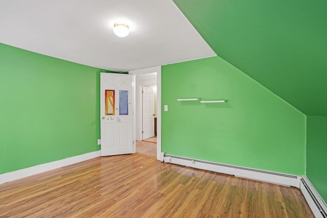 additional living space featuring light hardwood / wood-style floors, vaulted ceiling, and a baseboard radiator