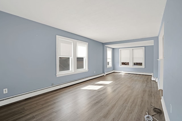 unfurnished living room with a baseboard heating unit and hardwood / wood-style floors