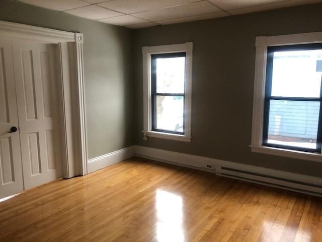 unfurnished bedroom featuring light wood-style floors, a paneled ceiling, and baseboards