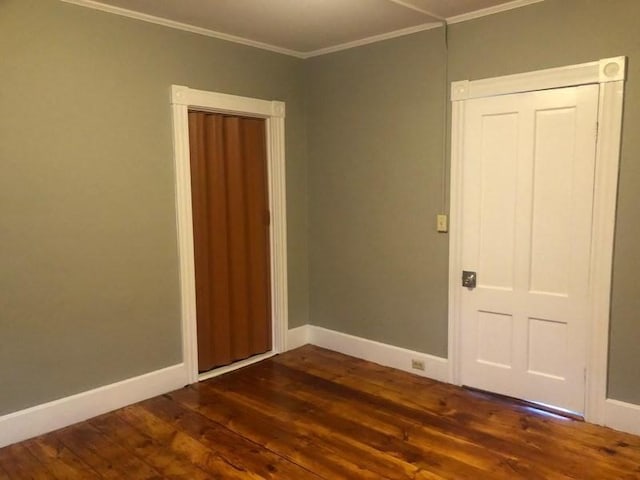 spare room with baseboards, ornamental molding, and dark wood-type flooring